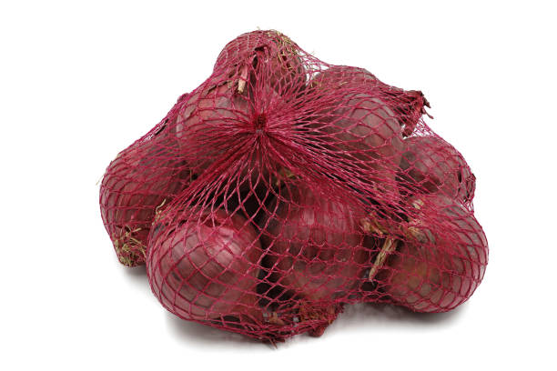 oignon rouge dans un sac net d’isolement sur le fond blanc - onion bag netting vegetable photos et images de collection