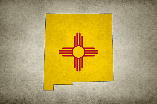 Grunge map of the state of New Mexico (USA) with its flag printed within its border on an old paper.