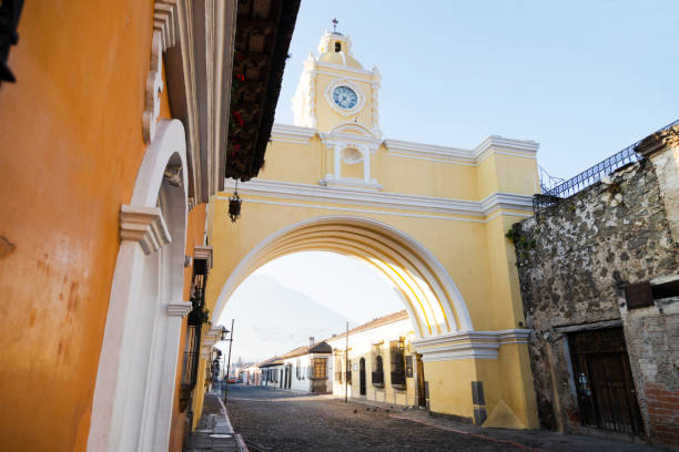 célèbre santa catalina arch et maisons coloniales dans l’avenue principale d’antigua guatemala - arc jaune coloré de la ville coloniale au guatemala tôt le matin - western europe europe indigenous culture traditional culture photos et images de collection