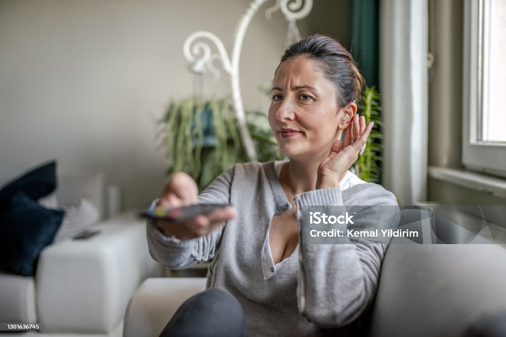 Young Adult Woman with Hearing Aid watching television Hearing Aid Stock Photo