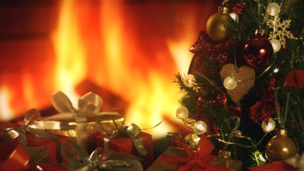 istock New Years Christmas festive background with burning fireplace. Christmas tree. Decorations, red gold balls and glowing bulbs on the tree. Warm home mood. Depth of field, soft focus 1301636790
