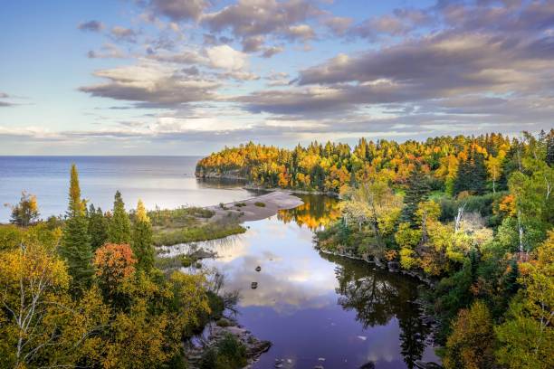 belles réflexions des nuages et des couleurs d’automne sur la rivière baptismal où il rencontre le lac supérieur au parc d’état de tettegouche, minnesota - great lakes photos et images de collection