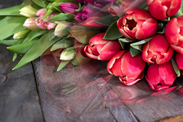 Bunch of fresh colorful tulips on old wooden boards. Spring background for mothers day and easter with space for text.