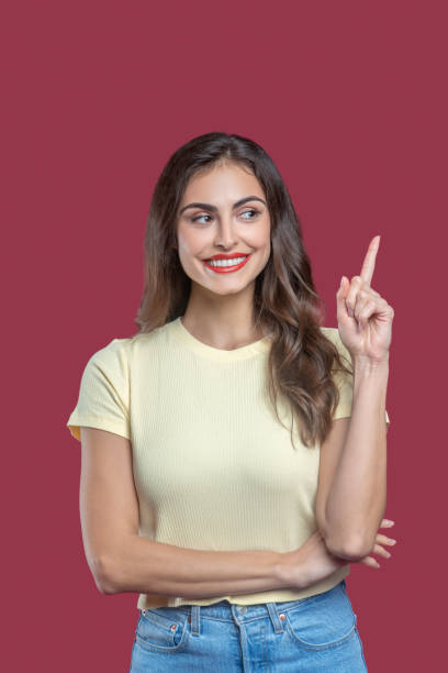 istock Smiling woman pointing finger up looking to side 1301640581