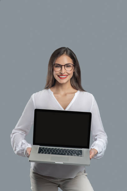 istock Joyful woman with glasses holding open laptop 1301640667