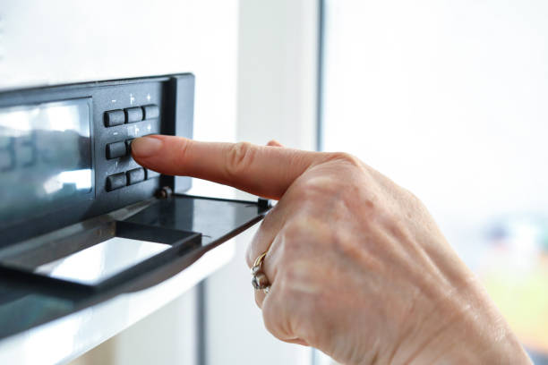 a mulher usa as chaves para ativar a caldeira de gás natural - boiler gas boiler thermostat control panel - fotografias e filmes do acervo