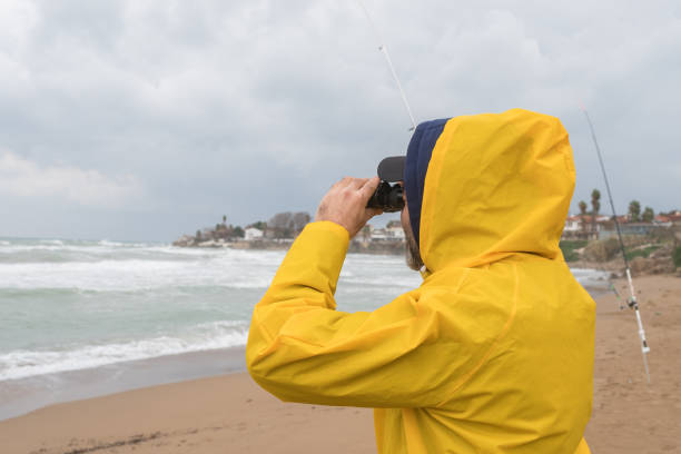 istock Fisherman looking away with binoculars on the beach in bad weather 1301643711