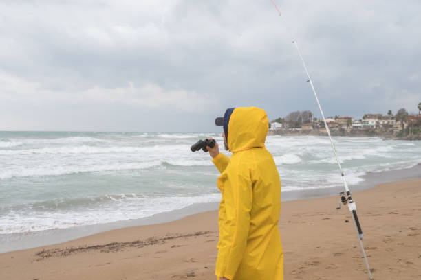 istock Fisherman looking away with binoculars on the beach in bad weather 1301643738