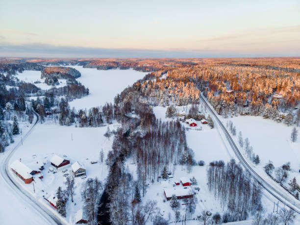 luftaufnahme des weißen winterwaldes mit schneebedeckten bäumen und landstraße in finnland - snow winter mountain horizon over land stock-fotos und bilder