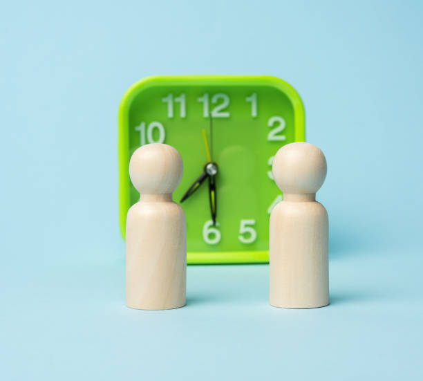 istock wooden figurines on green square clock background on blue background 1301644341