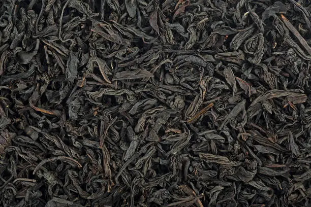 Large dry leaves of black tea. Black tea background. Black tea texture.