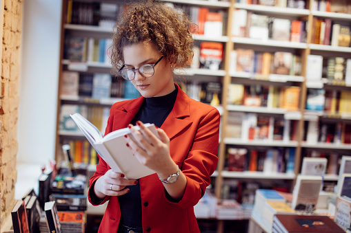 Young woman reading book. Young female student reading book at book store.