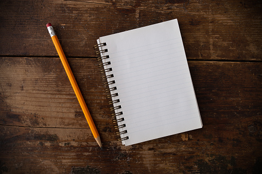 Blank notepad with pencil on wooden table