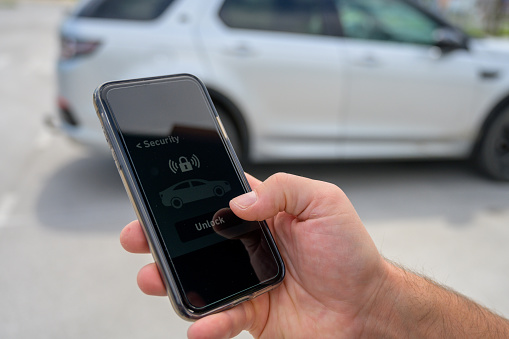 Close-up of male hand using smart phone to lock car.
Graphics were created by the contributor.