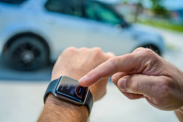 Close-up of male hands using smart watch to lock car.\nGraphics were created by the contributor.