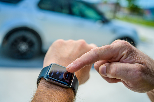 Close-up of male hands using smart watch to lock car.
Graphics were created by the contributor.