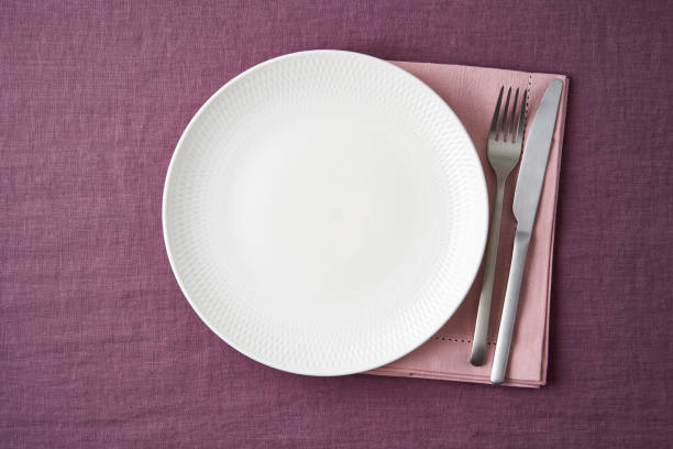 istock Clean empty white plate, fork and knife on bright blueberry red linen tablecloth on table, mockup 1301650954