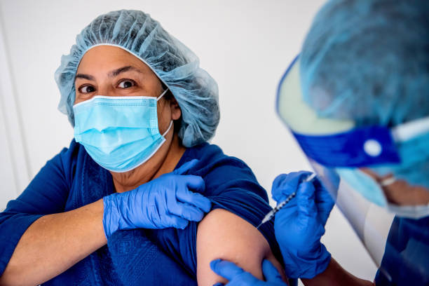 istock Female nurse being vaccinated by a coworker 1301654604