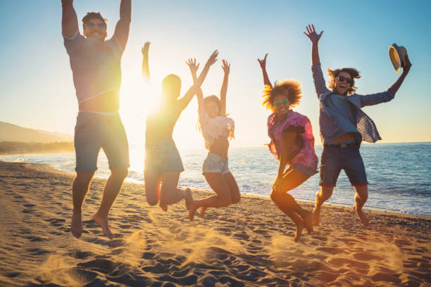 istock Group of friends jumping for joy on the beach at sunset or sunrise. 1301657607