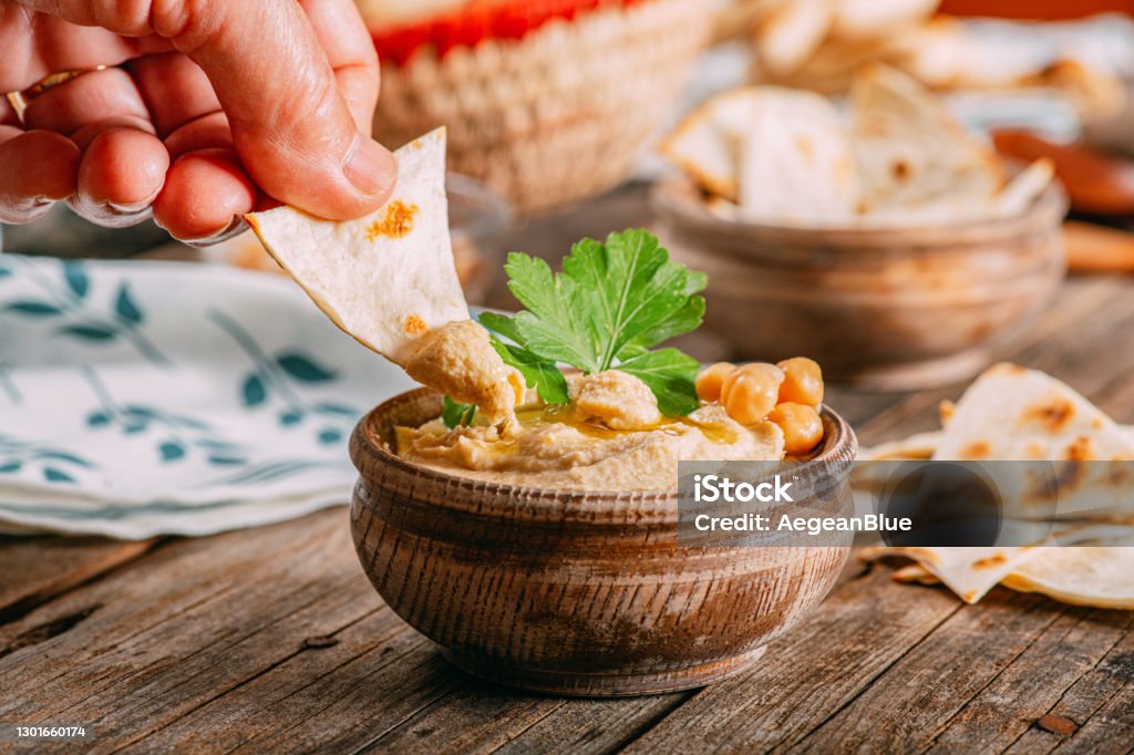 Traditional Vegan Food & Hand Dipping Hummus Hummus - Food Stock Photo
