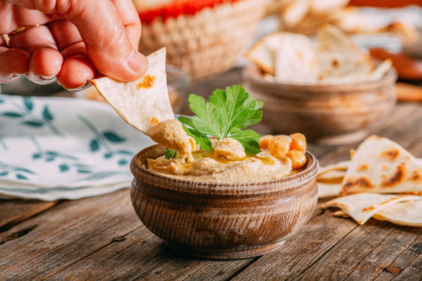 Traditional Vegan Food & Hand Dipping Hummus Traditional Vegan Food & Hand Dipping Hummus flatbread photos stock pictures, royalty-free photos & images