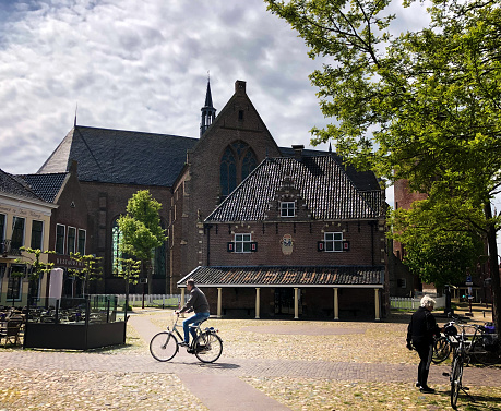 Amsterdam, Netherlands - May 7, 2017: Beursplein with parked bicycles motorcycles and Beurs van Berlage building former commodity exchange building now venue for concerts, exhibitions and conferences