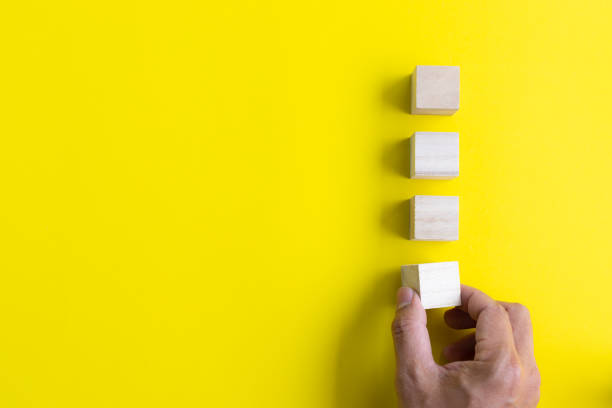 istock man hand putting blank wooden cube on yellow background with copy space. strategy idea concept. 1301672915