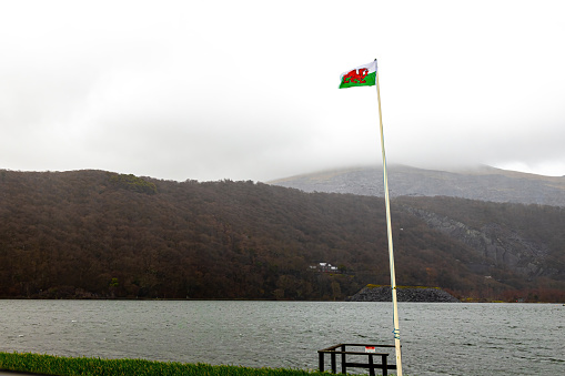 Welsh flag at the lake of Snowdonia at stormy weather, Wales, UK