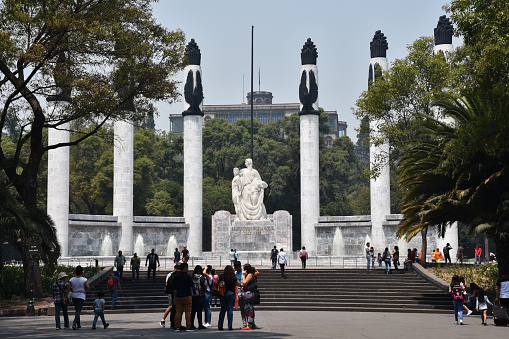 Mexico City, Mexico - May 14, 2019: The Altar a la Patria (Altar to the Homeland) monument by architect Enrique Aragón and sculptor Ernesto Tamariz, which is often called Monumento a los Niños Héroes (Monument to the Boy Heroes), and Chapultepec Castle in the Bosque de Chapultepec (park).