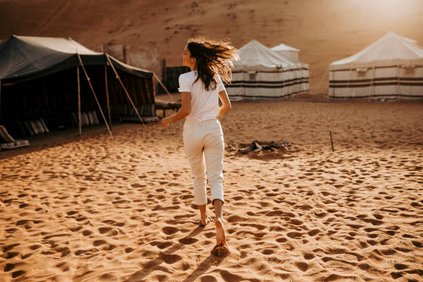 jovem relaxa fora do acampamento ao nascer do sol - oman - fotografias e filmes do acervo