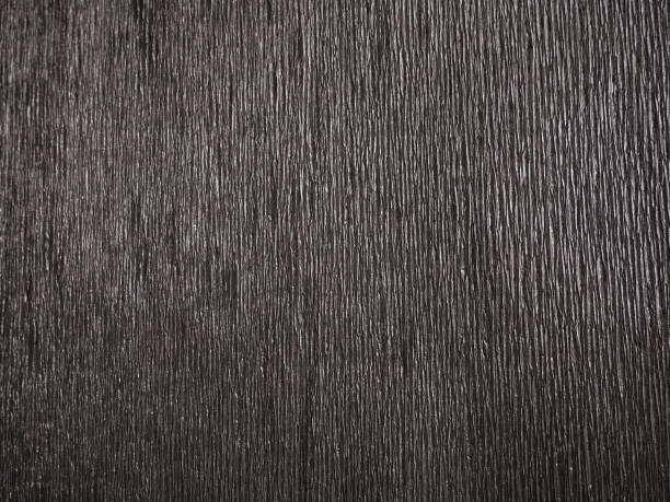 istock Black or gray corrugated paper. Uneven surface. Abstract monochrome background. Wavy edges of the paper sheet. Lighting gradient. Corrugated texture. 1301677305