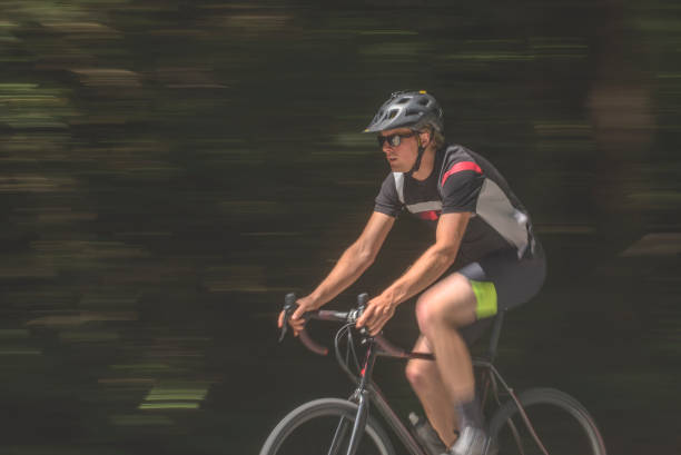 istock Young man road bikes past green forest in the morning 1301677355