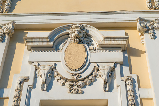 Bas-relief in the form of a muzzle of a lion above the window of an old building