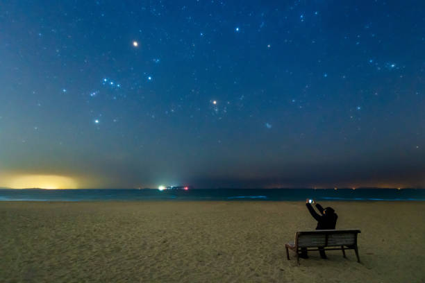 Night sky over shining ocean, nebula and lots of shiny stars with copy space.