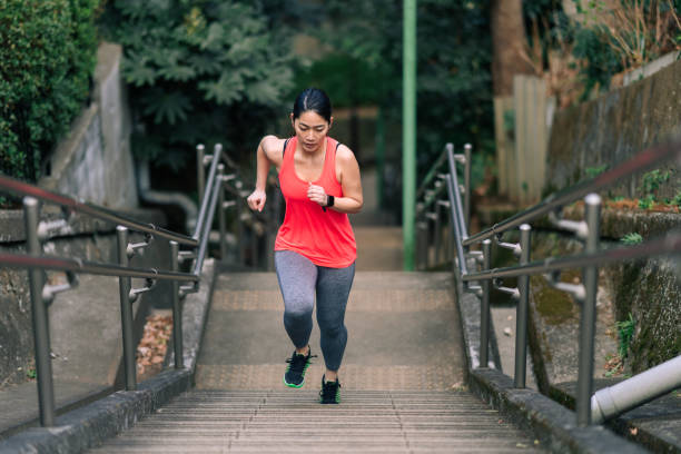 young female athlete running up stairs - asian ethnicity jogging female women imagens e fotografias de stock