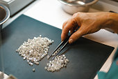 Manual sorting of diamonds. A hand with tweezers transfers diamonds from one pile to another