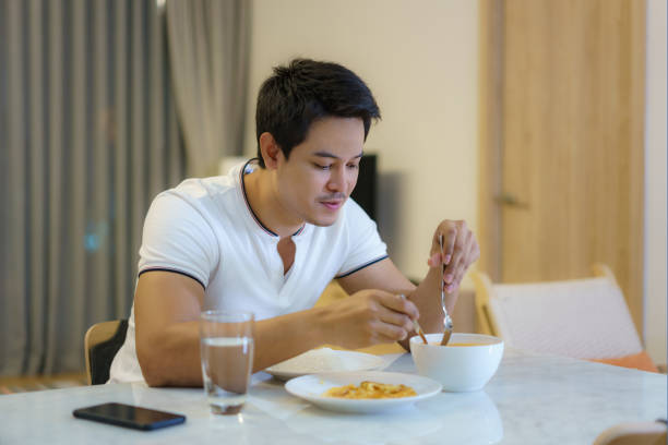 istock An Asian man is eating dinner alone at the dining table at night at home. 1301687767