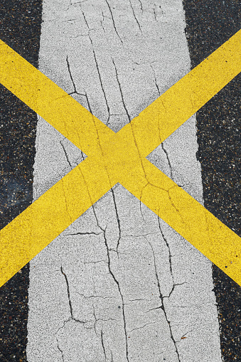 White and yellow traffic lines on the street, looks like a x crossing, with space for text, no person and vertical format