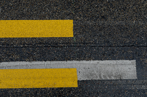 Asphalt marks with white and yellow stripes, texture as a background with white and yellow lines