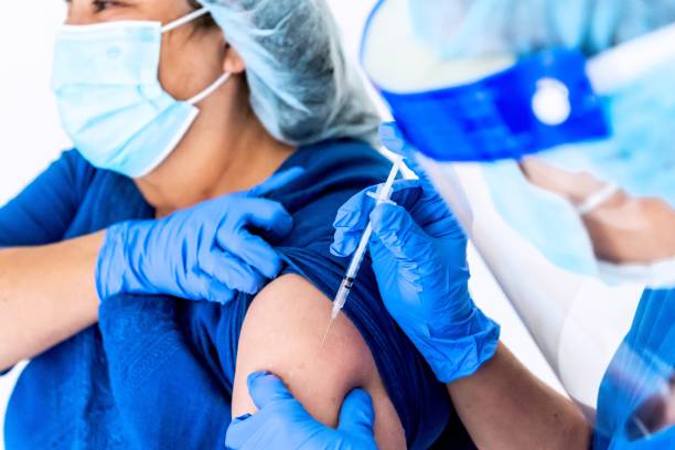 istock Female nurse being vaccinated by a coworker 1301694179