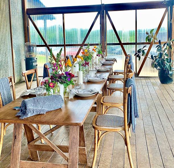 Alfresco Dining Table at The Farm Byron Bay Vertical long view of simple wooden rustic table setting with flowers at The Farm Restaurant Byron Bay NSW Australia outdoor dining photos stock pictures, royalty-free photos & images