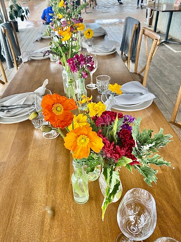 Vertical long view of simple wooden rustic table setting with colorful flowers at The Farm Cafe Restaurant Byron Bay NSW Australia