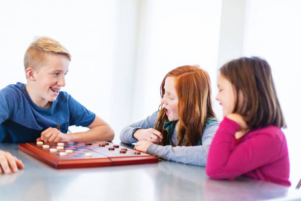 istock Three Siblings Playing checkers together at Dining Table Photo Series 1301702478