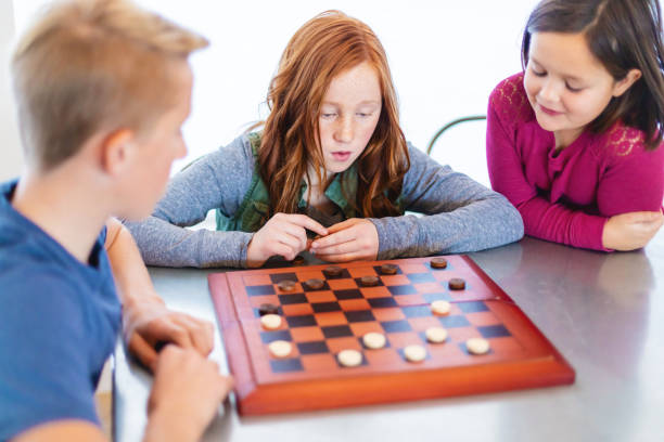 istock Three Siblings Playing checkers together at Dining Table Photo Series 1301702493