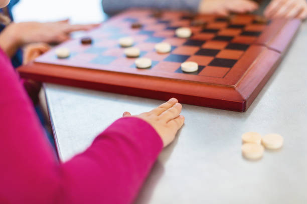 istock Three Siblings Playing checkers together at Dining Table Photo Series 1301702519