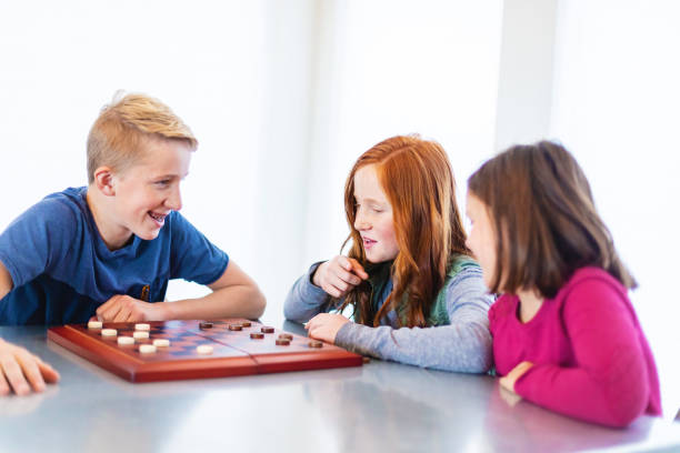 istock Three Siblings Playing checkers together at Dining Table Photo Series 1301702521