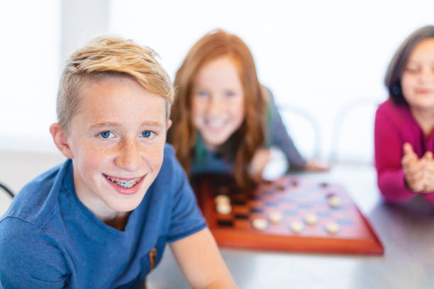 istock Three Siblings Playing checkers together at Dining Table Photo Series 1301702553