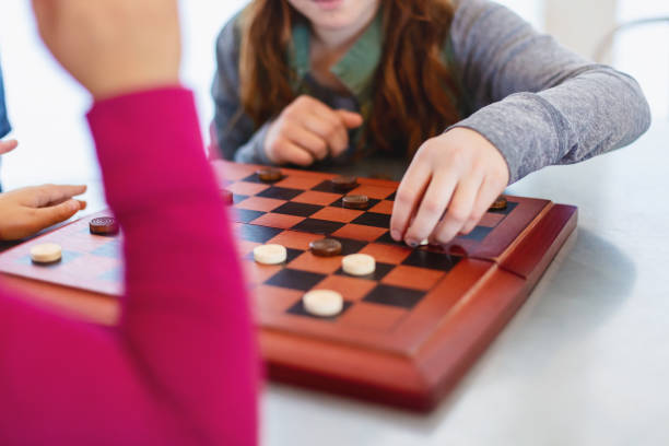 istock Three Siblings Playing checkers together at Dining Table Photo Series 1301702584