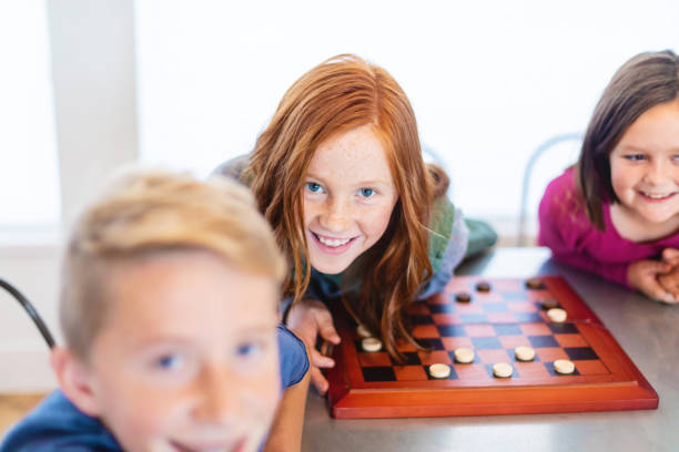 istock Three Siblings Playing checkers together at Dining Table Photo Series 1301702588