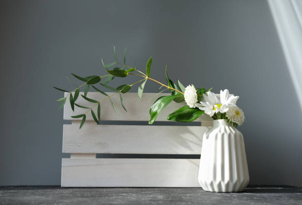 istock white vase with white flowers and green leaves. 1301704577